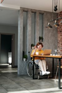 Woman in wheelchair smiling and waving at laptop